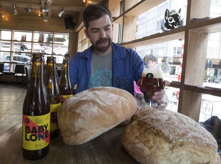 Sebastien Morvan, one of the founders of microbrewery Brussels Beer Project, displays bread and looks at a beer called Babylone at Barbeton bar in central Brussels, April 14, 2015. REUTERS/Yves Herman