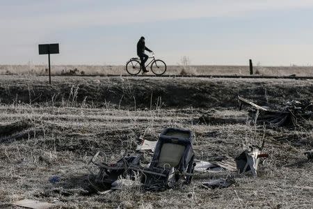 A man rides his bicycle past the wreckage of the Malaysia Airlines Flight MH17, near the village of Hrabove (Grabovo) in Donetsk region, in this December 15, 2014 file photo. REUTERS/Maxim Shemetov/Files