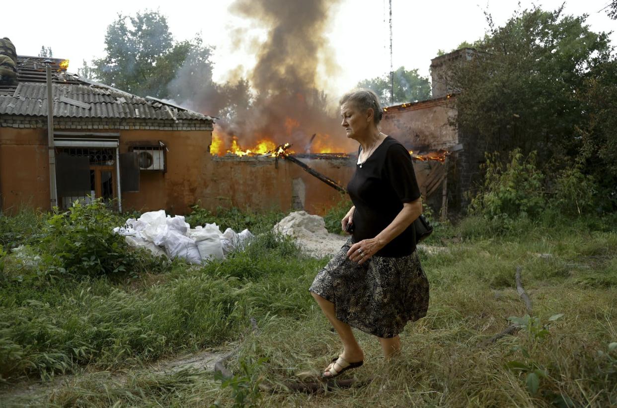 A woman runs from a house on fire after shelling in Donetsk in eastern Ukraine in June 2022. <a href="https://newsroom.ap.org/detail/PicturesoftheWeek-Global-PhotoGallery/2ca5448f82104d6d8c3f0d8af53de065/photo" rel="nofollow noopener" target="_blank" data-ylk="slk:AP Photo/Alexei Alexandrov;elm:context_link;itc:0;sec:content-canvas" class="link ">AP Photo/Alexei Alexandrov</a>