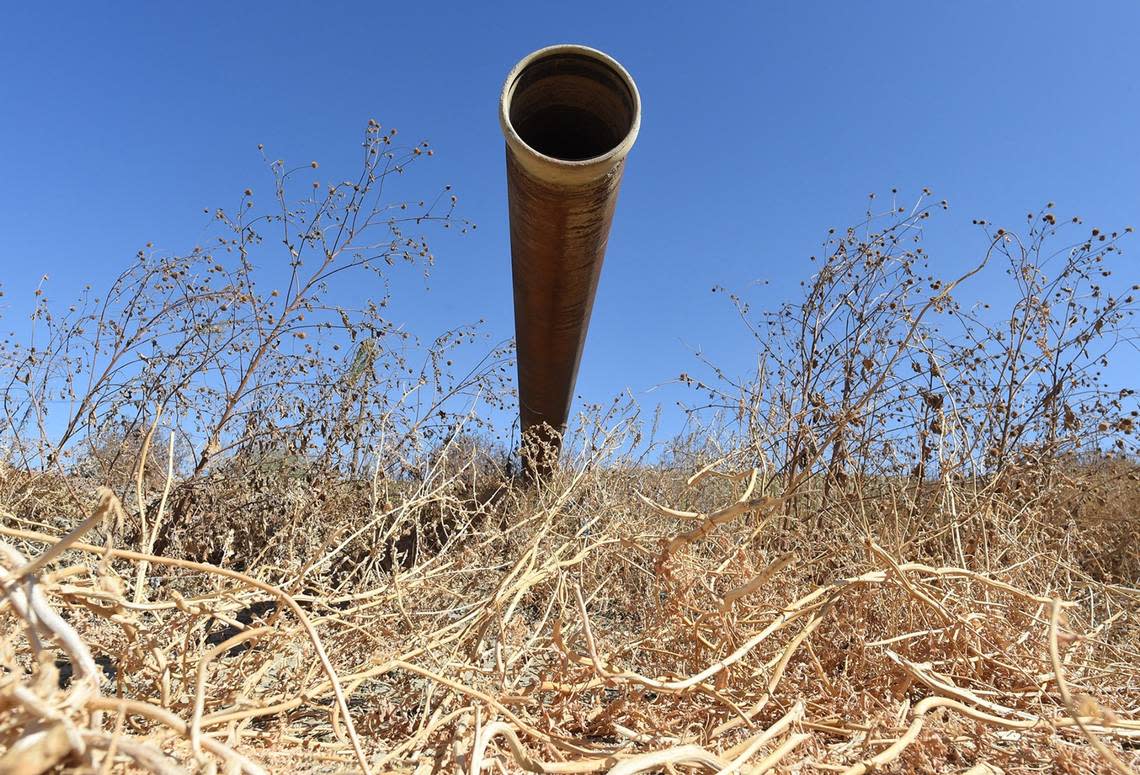 A pipe used to direct runoff water sits idle next to a fallow melon field in western Fresno County, Oct. 12, 2021.