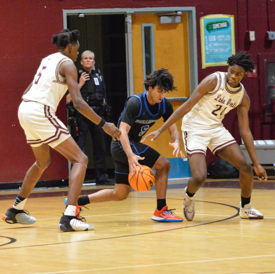 Wellington's Jeremy Tovar attempts to dribble past Lake Worth's Chasion Wilson and Jeremy Innocent on Feb. 15, 2024.