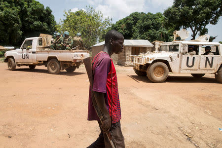 FILE PHOTO: A member of the Anti-Balaka armed militia walks next to United Nations peacekeeping soldiers in the village of Makunzi Wali, Central African Republic, April 27, 2017. Picture taken April 27, 2017. REUTERS/Baz Ratner/File Photo