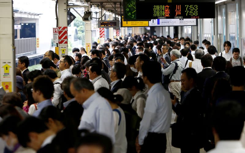 FILE PHOTO: Passengers wait for a train on a platform at a station in Kawasaki, Japan