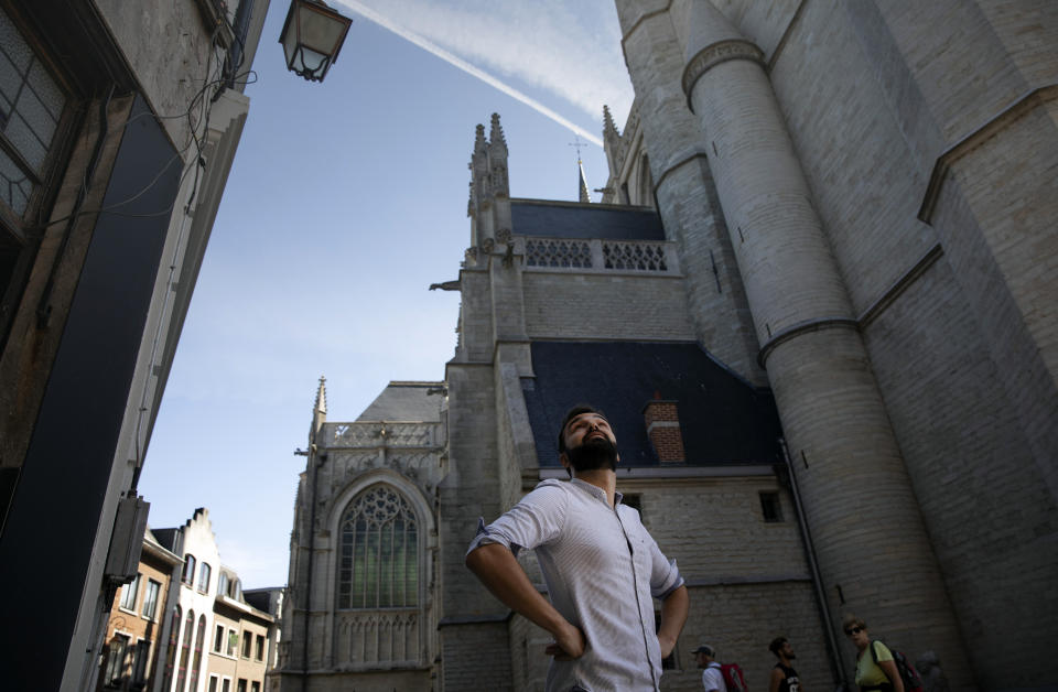 In this photo taken on Wednesday, June 24, 2020, history teacher Andries Devogel looks up toward a falcon nest on the Saint Martin Basilica in Halle, Belgium. Much responsibility will be put on young history teachers like Andries Devogel in the coming decade, with the expectation to stress the impact of colonialism on current-day society. (AP Photo/Virginia Mayo)