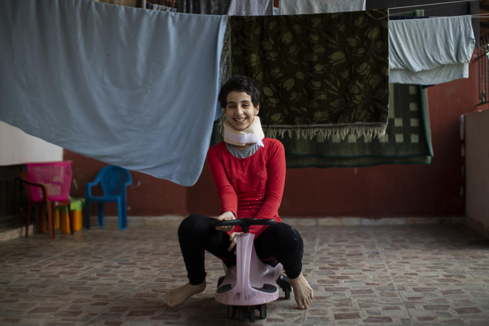 Hoda Kinno, 11, smiles as she plays in a temporary apartment in the coastal town of Jiyeh, south of Beirut, Lebanon, Tuesday, Sept. 22, 2020. The Kinno family from Syria's Aleppo region was devastated in the wake of the Aug. 4 explosion at the Beirut port -- Hoda suffered a broken neck and other injuries and her sister Sedra, 15, died in the explosion. (AP Photo/Hassan Ammar)