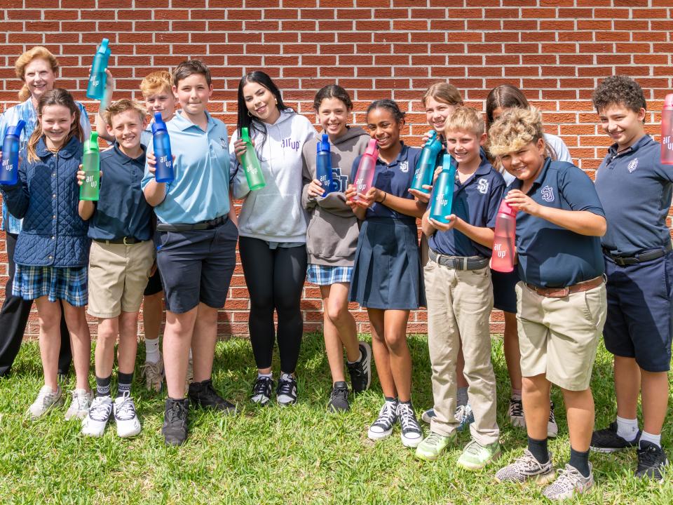 St. Johns Country Day School sixth-grader Grayson Kalch, front third from left, fellow science students and teacher Tina Sachs, far left rear, display the air pp water bottles and scent pods they were sent for a class project.