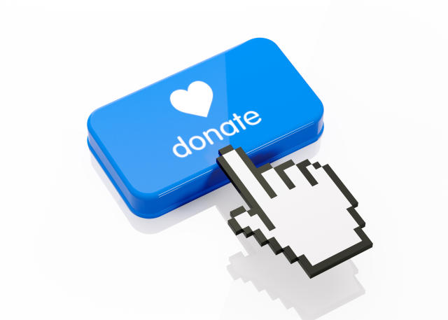 Hand shaped computer cursor is clicking on a blue computer button on white reflective surface. Donate writes on button. Horizontal composition with copy space and clipping path.  Donation and charity concept.