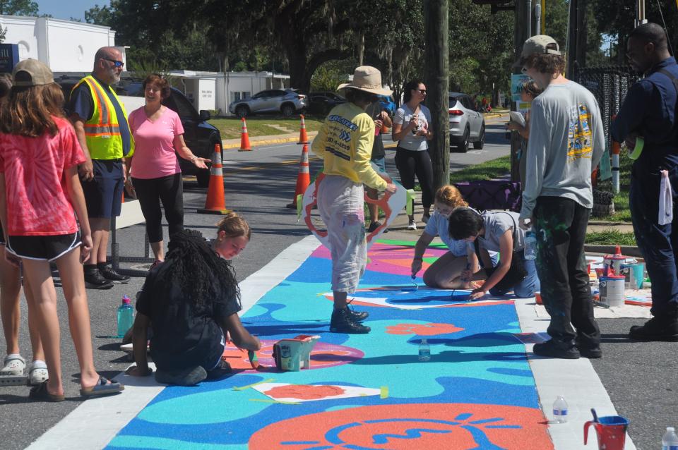 Volunteers painting a crosswalk in the city.