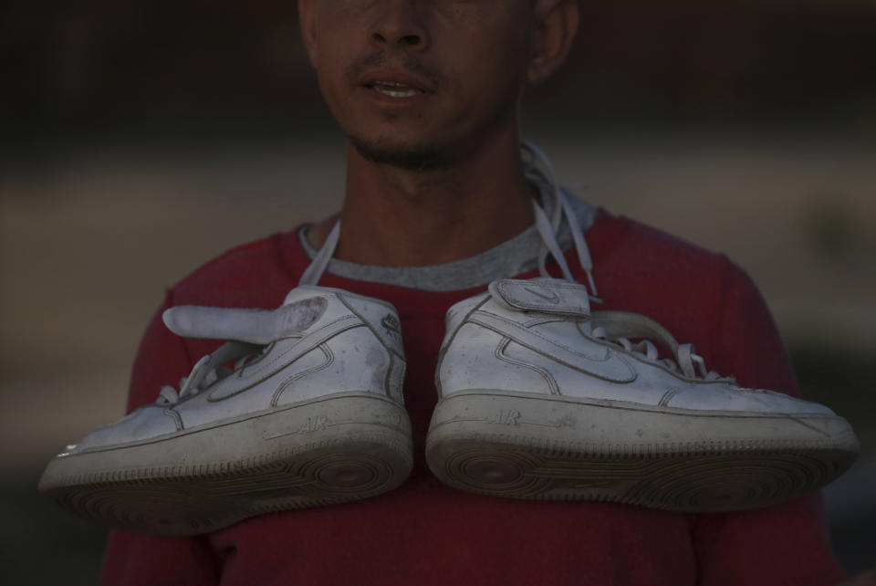 A Venezuelan migrant carries his shoes around his neck before crossing toward the United States border to surrender to the border patrol, in Ciudad Juarez, Mexico, Thursday, Oct. 13, 2022. The U.S. announced on Oct. 12, that Venezuelans who walk or swim across the border will be immediately returned to Mexico without rights to seek asylum. (AP Photo/Christian Chavez)