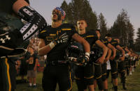 FILE - In this Aug. 23, 2019 file photo, members of the Paradise High School football team stand for the playing of the national anthem before their game against Williams High School in Paradise, Calif. Paradise, the Northern California high school football team is preparing to play for a championship one year after most of the players and coaches lost their homes to a wildfire that nearly destroyed their town. Paradise High School will face Sutter Union High School on Saturday, Nov. 30 for the Northern Section Division III championship.(AP Photo/Rich Pedroncelli, File)