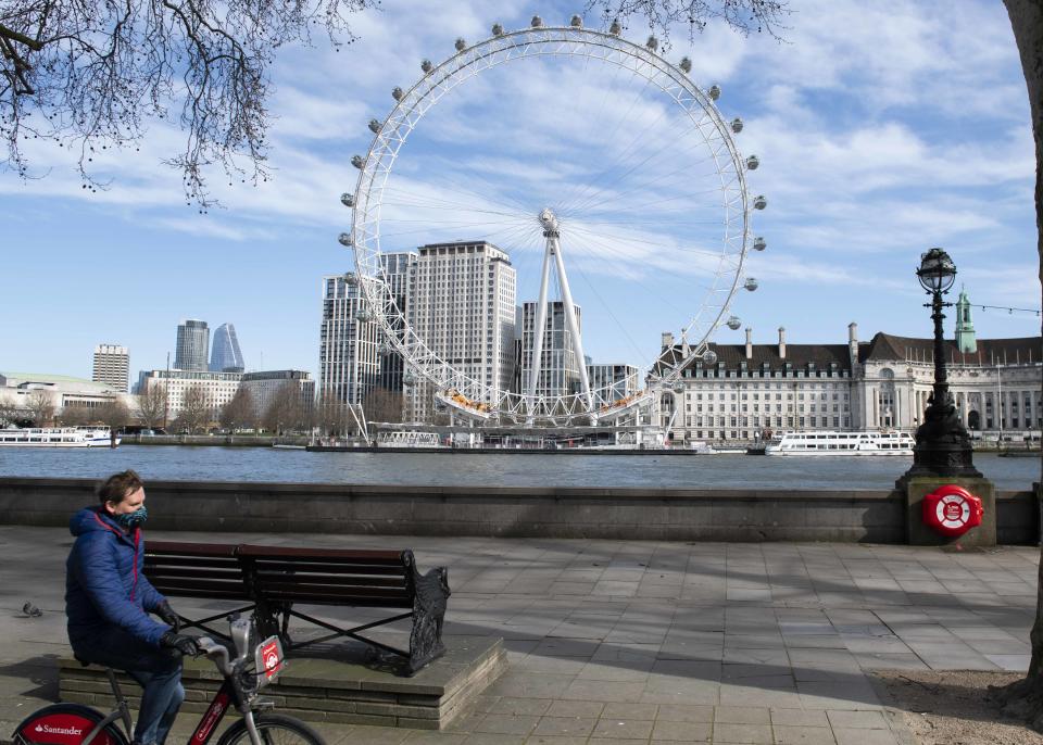 A member of the public wearing a protective mask cycles past an empty London Eye, during the Corona Virus outbreak, London.  Picture date: Monday 23rd March 2020.  Photo credit should read:  David Jensen/ EMPICS Entertainment