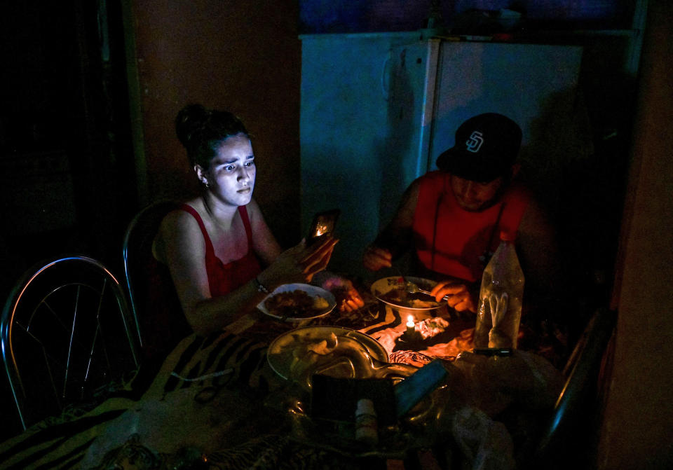 A woman looks at her phone while eating by candlelight during a blackout in Havana on May 25, 2022. (Yamil Lage / AFP via Getty Images)