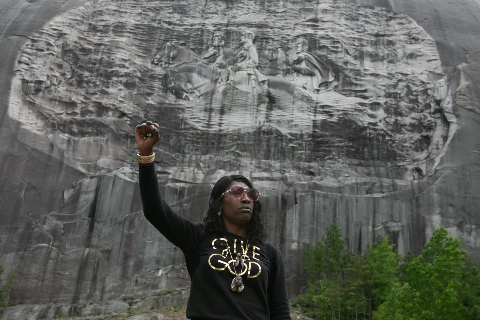 Lahahuia Hanks holds up a fist in front of the Confederate carving at Stone Mountain Park during a Black Lives Matter protest on June 16, 2020 in Stone Mountain, Georgia.  / Credit: Jessica McGowan/Getty Images