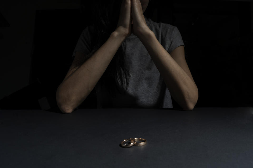 Wedding bands on a table while a person has their hands in prayer position