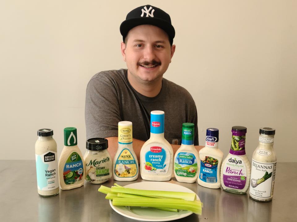 Lucien Formichella posing with nine bottles of ranch dressing.