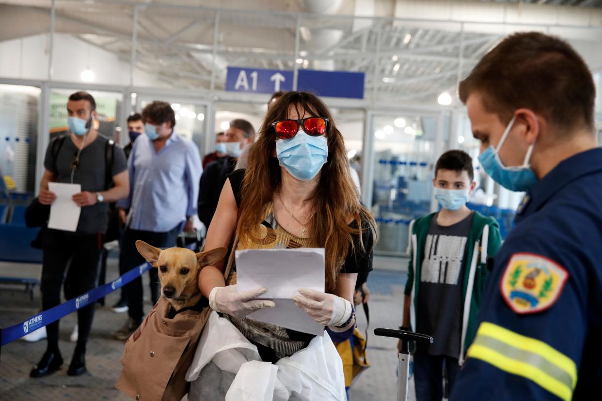 A firefighter directs passengers who arrived to the Eleftherios Venizelos International Airport in Athens, Monday, June 15, 2020. The Centers for Disease Control recently moved Greece to its "Level 4: COVID-19 Very High" travel advisory category.