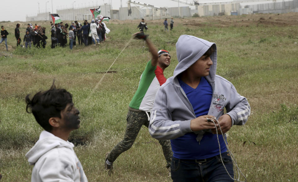 A protester hurls stones near the fence of the Gaza Strip border with Israel, marking first anniversary of Gaza border protests east of Gaza City, Saturday, March 30, 2019. Tens of thousands of Palestinians on Saturday gathered at rallying points near the Israeli border to mark the first anniversary of weekly protests in the Gaza Strip, as Israeli troops fired tear gas and opened fire at small crowds of activists who approached the border fence. (AP Photo/Adel Hana)