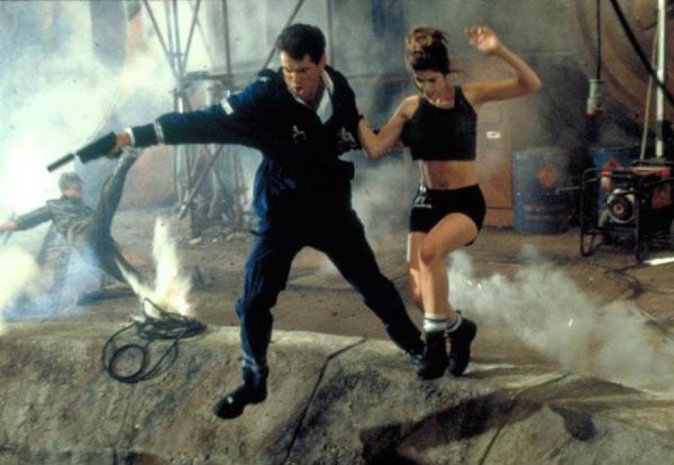 Pierce Brosnan and Denise Richards holding hands and jumping