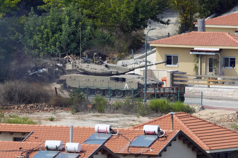 An Israeli tank deploys between houses in the Israeli town of Metal, as seen from the Lebanese side of the Lebanese-Israeli border in the southern village of Kfar Kila, Lebanon, Monday, Oct. 9, 2023. Israel's military battled to drive Hamas fighters out of southern towns and seal its borders Monday, as it pounded the Gaza Strip from the air and mustered for a campaign its prime minister said would destroy "the military and governing capabilities" of the militant group. (AP Photo/Hassan Ammar)