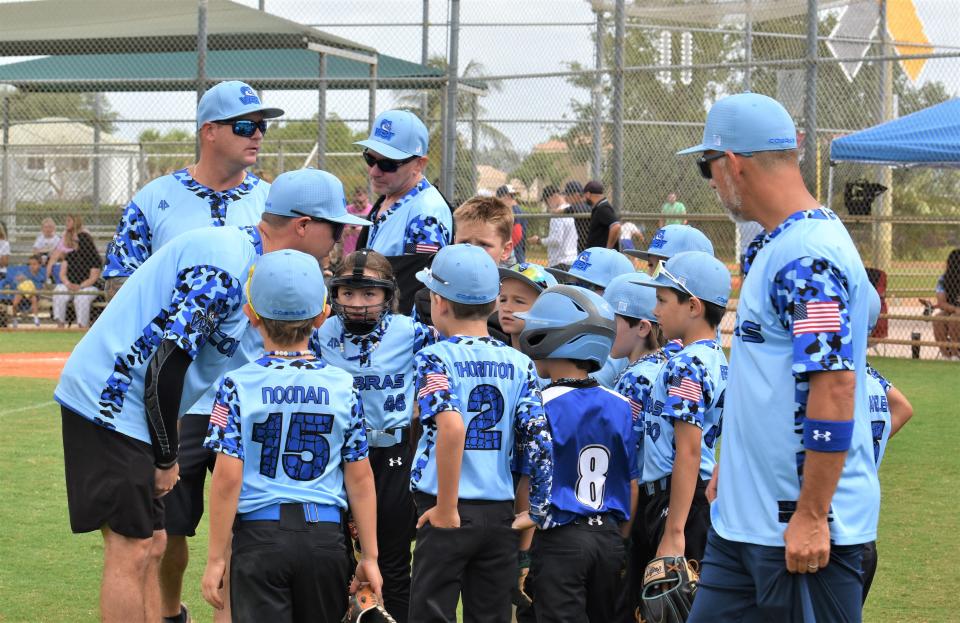 West Boynton Travel league head coach Jerry Parker and his Cobras assistants give advice to their players in between innings of a game on April 28, 2024.
