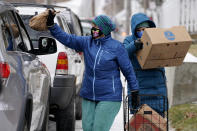 Joan Beal, left, and Mindy Butler wear face coverings to help prevent the spread of coronavirus while handing out pet food at a drive-thru food pantry outside the First Universalist Church, Wednesday, Nov. 25, 2020, in Norway, Maine. (AP Photo/Robert F. Bukaty)