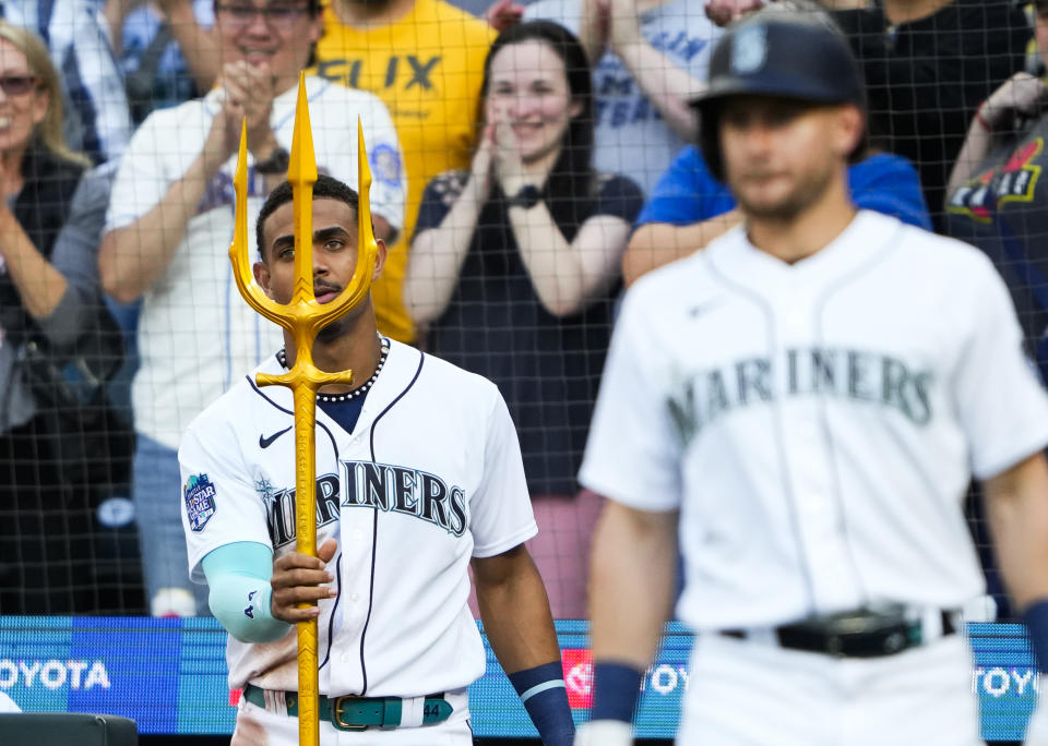 Seattle Mariners' Julio Rodriguez, left, holds a trident as he waits for teammate Eugenio Suarez to arrive in the dugout after Suarez hit a home run against the Washington Nationals during the fourth inning of a baseball game Monday, June 26, 2023, in Seattle. (AP Photo/Lindsey Wasson)