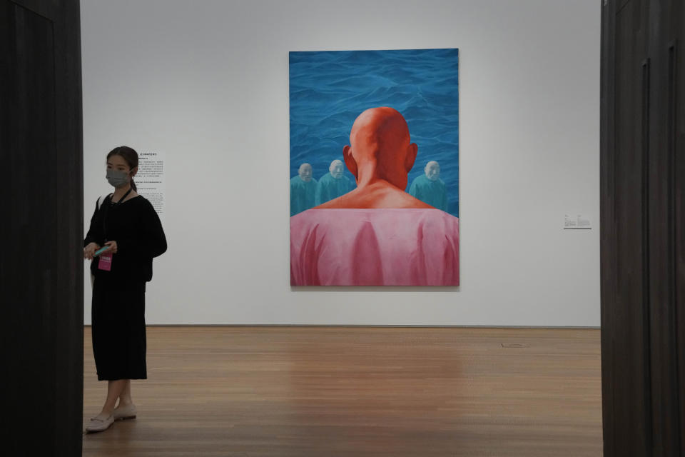 A woman walks past the artwork "1995.2" created by Chinese artist Fang Lijun during a media preview in the West Kowloon Cultural District of Hong Kong, Thursday, Nov. 11, 2021. Hong Kong's swanky new M+ museum _ Asia's largest gallery with a billion-dollar collection _ is set to open on Friday amid controversy over politics and censorship. (AP Photo/Kin Cheung)