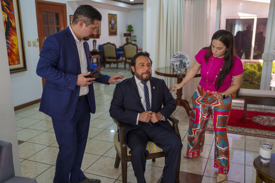 Staffers adjust a chair for El Salvador Vice President Félix Ulloa, who is running for re-election as the runningmate of President Nayib Bukele, for an interview at his office in San Salvador, El Salvador, Tuesday, Jan. 30, 2024. El Salvador will hold its presidential election on Feb. 4. (AP Photo/Moises Castillo)