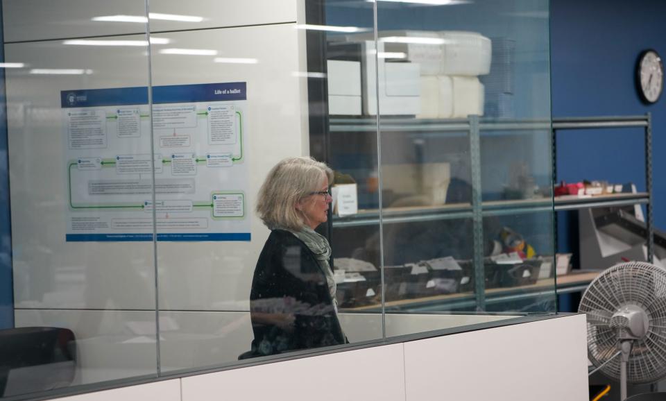 A woman watches ballot processing at the Washoe County Registrar of Voters office from a glassed-in observation booth. It was installed so the public could watch the process without interrupting workers, following concerns about harassment during a previous election.