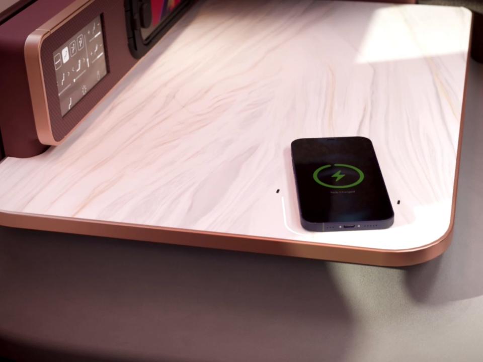 A phone on the tray table showing its wireless charging.
