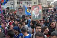 FILE - In this Feb. 11, 2014 file photo released by the Syrian official news agency SANA, supporters of Syrian President Bashar Assad, hold up his portraits as they march during a demonstration is solidarity with government forces, in the al-Inshaat neighborhood of Homs, Syria. As the Syrian conflict entered its forth year this month and large parts of the country are either destroyed or under opposition control, Syrian officials say the presidential elections will be held on time later this year.The opposition rejects such a move saying after the death of more than 140,000 people and millions turned to refugees or displaced, Assad should step down rather than run again. (AP Photo/SANA, File)