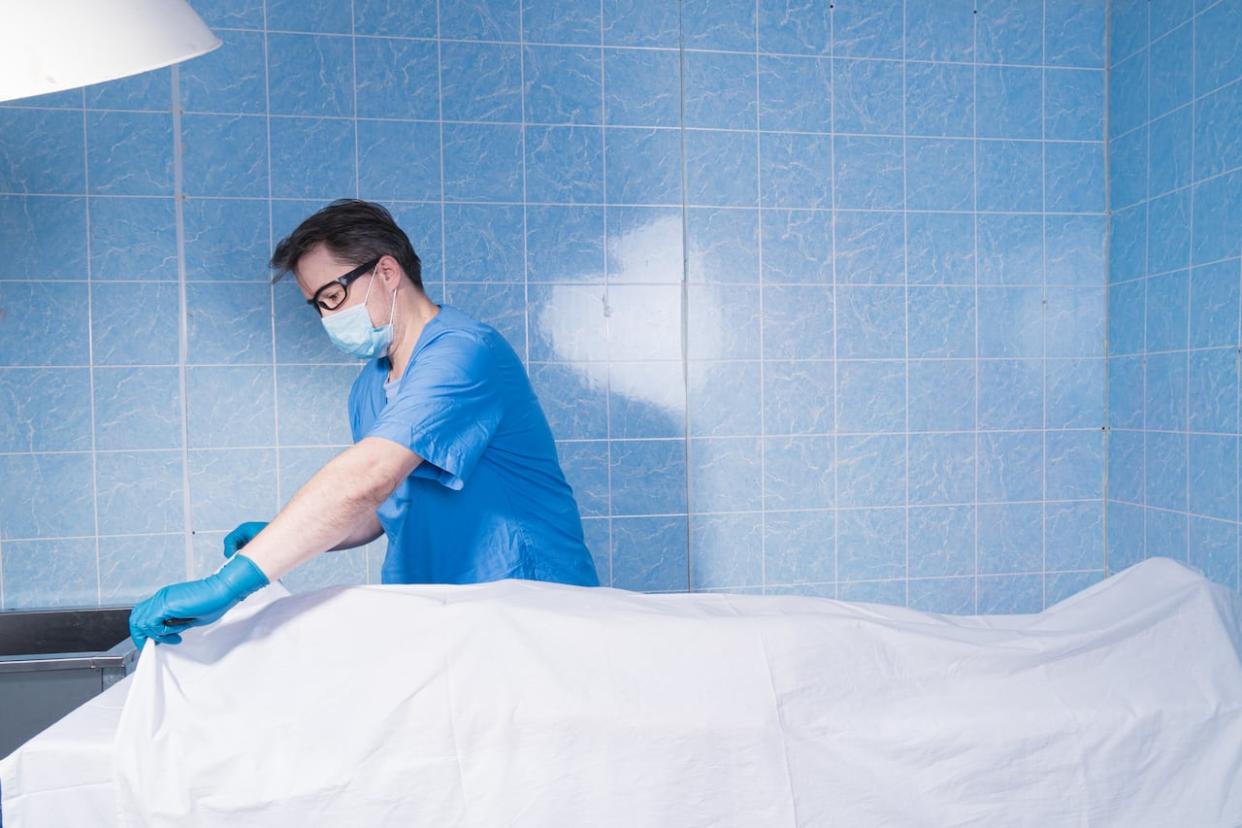 Stock image shows a coroner covering up a body. In Ontario, the number of bodies going unclaimed is surging, according to the province's chief coroner. (Shutterstock - image credit)