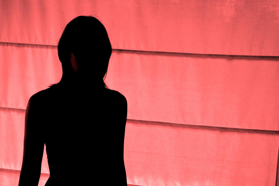 Woman in shadow in front of pink wall represents sex workers left behind in COVID-19 brothel lock down