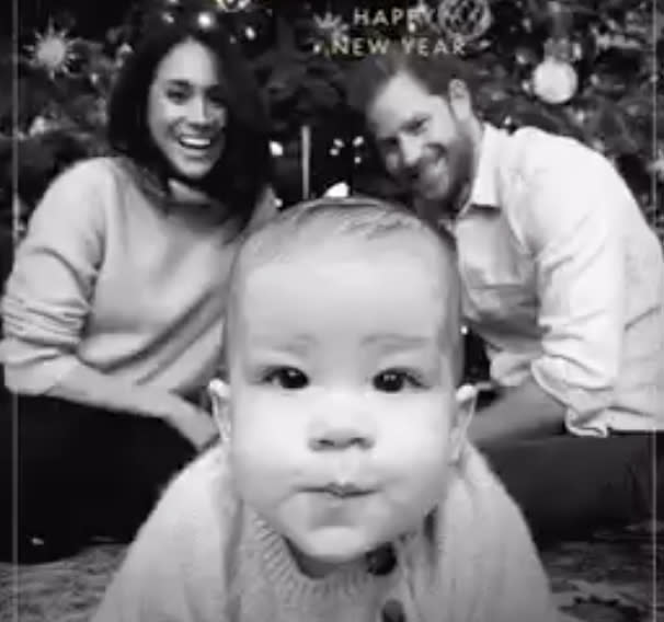 Meghan Markle and Prince Harry watch Archie in the foreground if the photo staring into the camera