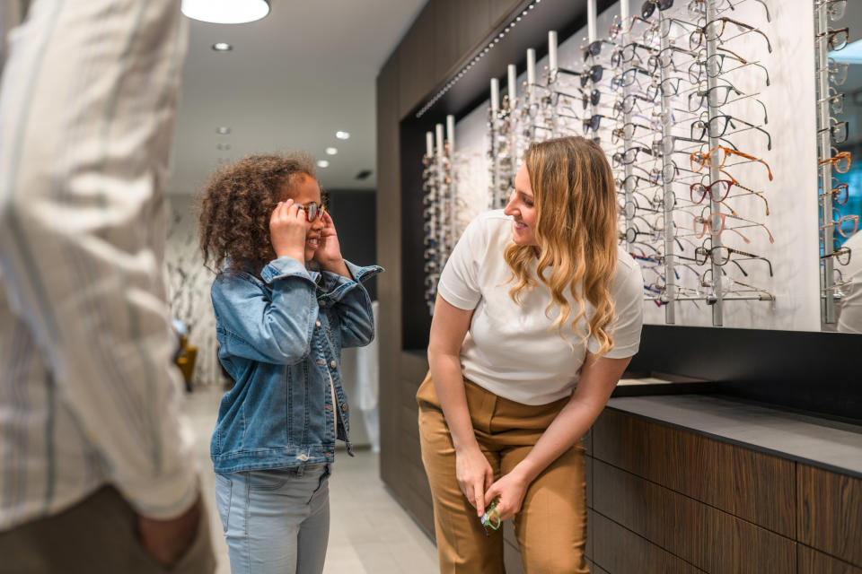 a young girl shopping for eye glasses in a store