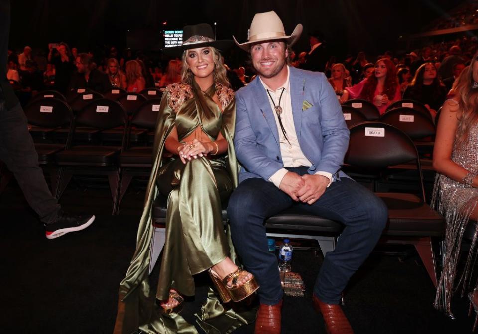 lainey wilson and devlin hodges sitting in their seats for an awards show and smiling for a photo