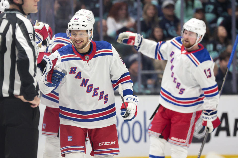 New York Rangers left wing Artemi Panarin, left, celebrates with the team bench after scoring during the first period of an NHL hockey game against the Seattle Kraken, Saturday, Oct. 21, 2023, in Seattle. (AP Photo/Jason Redmond)