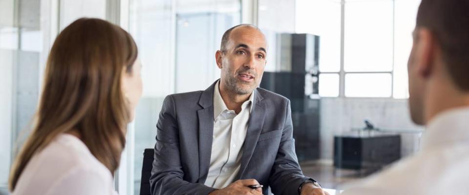 Mature financial agent explaining credit cards to young couple