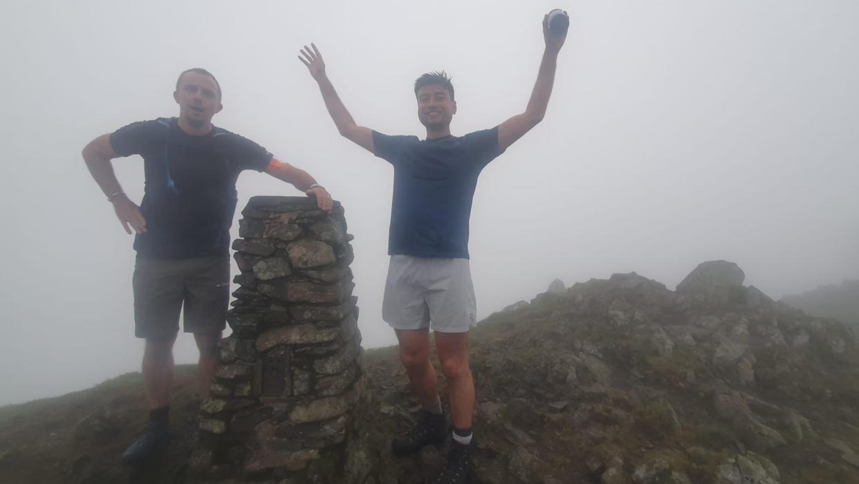 Two men at the top of a foggy mountain peak in the Lake District