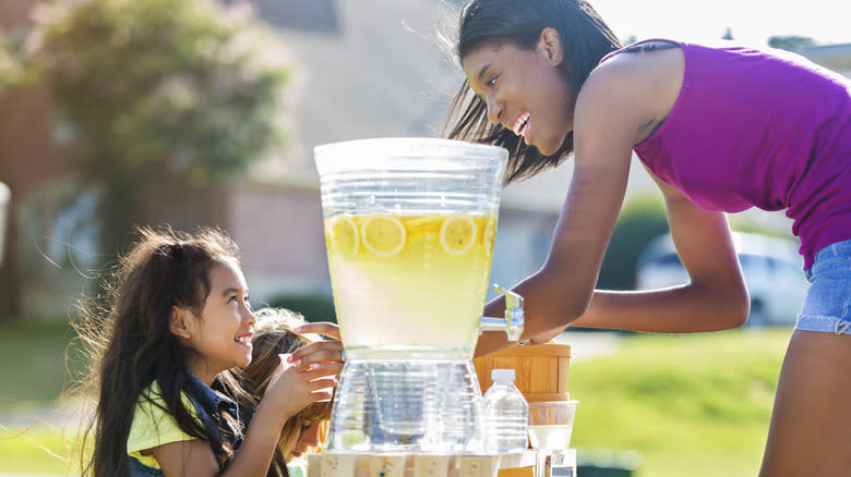 woman giving lemonade to girl