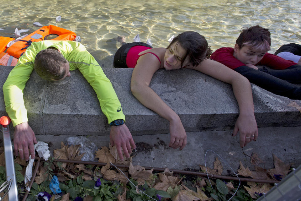 Activists lie in the Cibeles fountain during a protest performance in Madrid, Spain, Tuesday, Dec. 3, 2019. Some 20 activists from the international group called Extinction Rebellion cut off traffic in central Madrid and staged a brief theatrical performance to protest the climate crisis. The activists held up a banner in Russian that read "Climate Crisis. To speak the truth. To take action immediately." Some 10 others dressed in red robes and with their faces whitened to symbolize the human species' peril danced briefly before police moved in to end the protest. (AP Photo/Paul White)