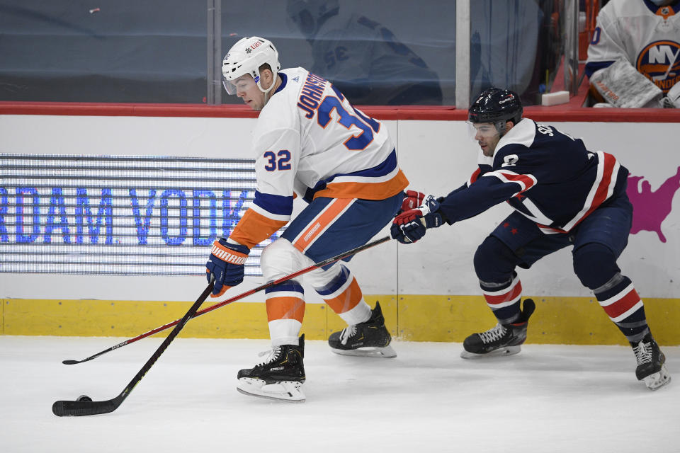 New York Islanders left wing Ross Johnston (32) skates with the puck next to Washington Capitals defenseman Justin Schultz (2) during the first period of an NHL hockey game Tuesday, Jan. 26, 2021, in Washington. (AP Photo/Nick Wass)