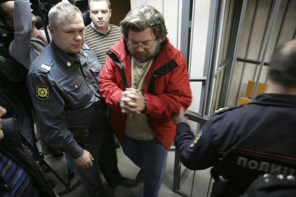 Greenpeace International spokesperson Roman Dolgov is escorted to a defendants' box at the Leninsky District Court Of Murmansk