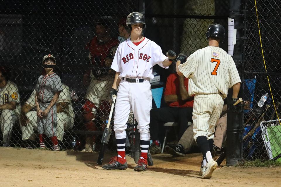 Joe Corsi, the son of the the late Red Sox pitcher Jim Corsi, fist bumps a teammate before heading up to bat during the 28th annual Abbot Financial Management Oldtime Baseball Game in Cambridge, Aug. 24, 2022.