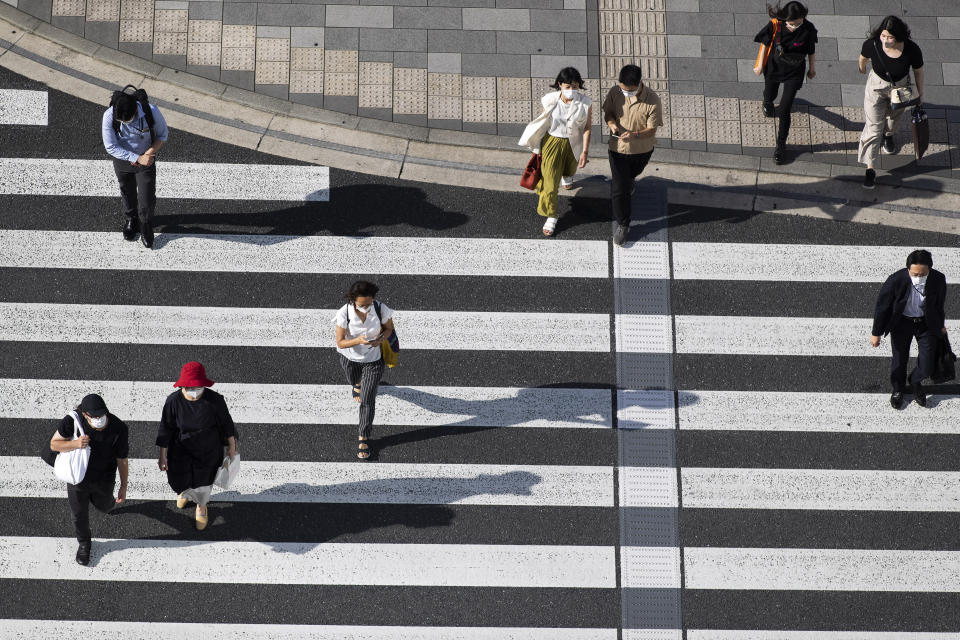 People wearing face masks walk across an intersection in Tokyo on Thursday, July 15, 2021. (AP Photo/Hiro Komae)