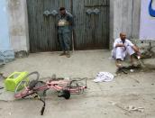 An injured man (R) sits at the site after a suicide bomb blast in Jalalabad April 18, 2015. (REUTERS/Parwiz)