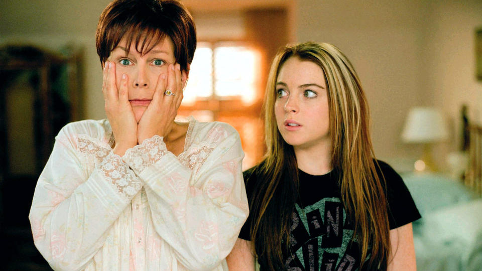 Jamie Lee Curtis looks in the mirror, surprised, as Lindsay Lohan looks on.