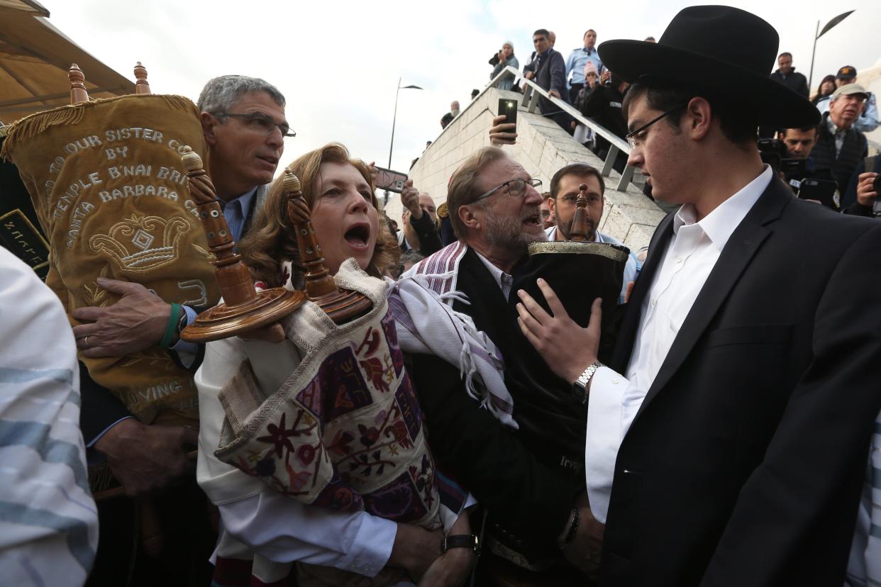 An ultra-Orthodox Jewish man tries to prevent Anat Hoffman (center), the founder and president of Women of the Wall, and members of the liberal group from entering the women's section of the Western Wall while carrying a Torah scroll in Jerusalem in November 2016 during a protest by the group demanding equal prayer rights at the site. (Photo: MENAHEM KAHANA via Getty Images)