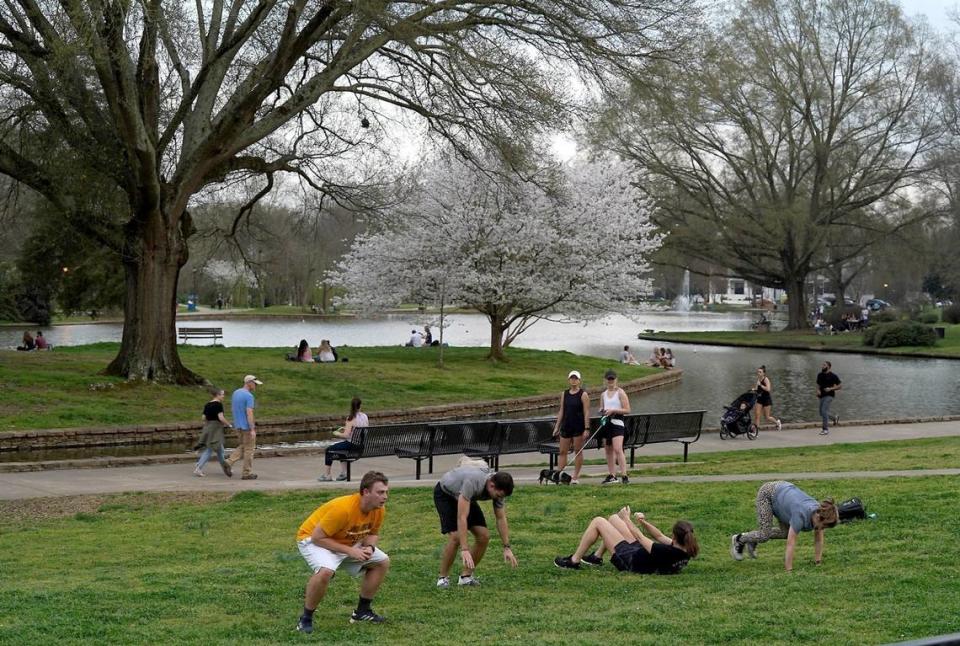 People exercise near the band shell at Freedom Park as others enjoy a walk or run on Thursday, March 19, 2020.