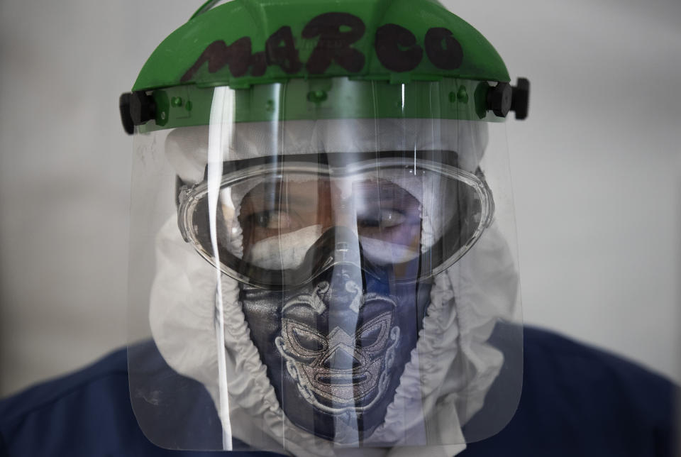 Healthcare worker Marco Antonio Galicia wears a protective face mask designed with a Mexican wrestler motif, in a ward designated for COVID-19 patients, at the Ajusco Medio General Hospital in Mexico City, Thursday, Nov. 19, 2020. (AP Photo/Marco Ugarte)